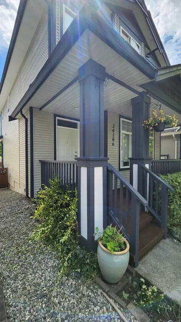 Finished front porch with charcoal-blue columns, white panels and repainted railings in sunlight