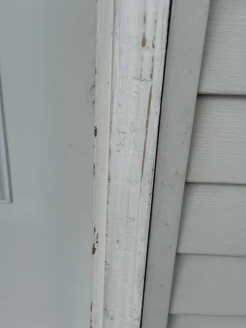 Close-up of peeling, weathered paint on an exterior door casing before preparation